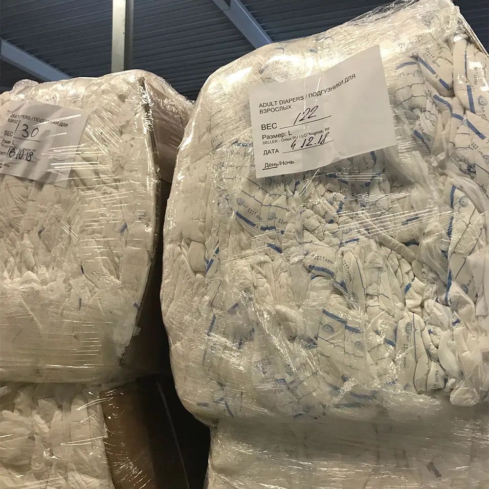 Large compressed bundles of adult diapers wrapped in clear plastic with labels in Russian and English.