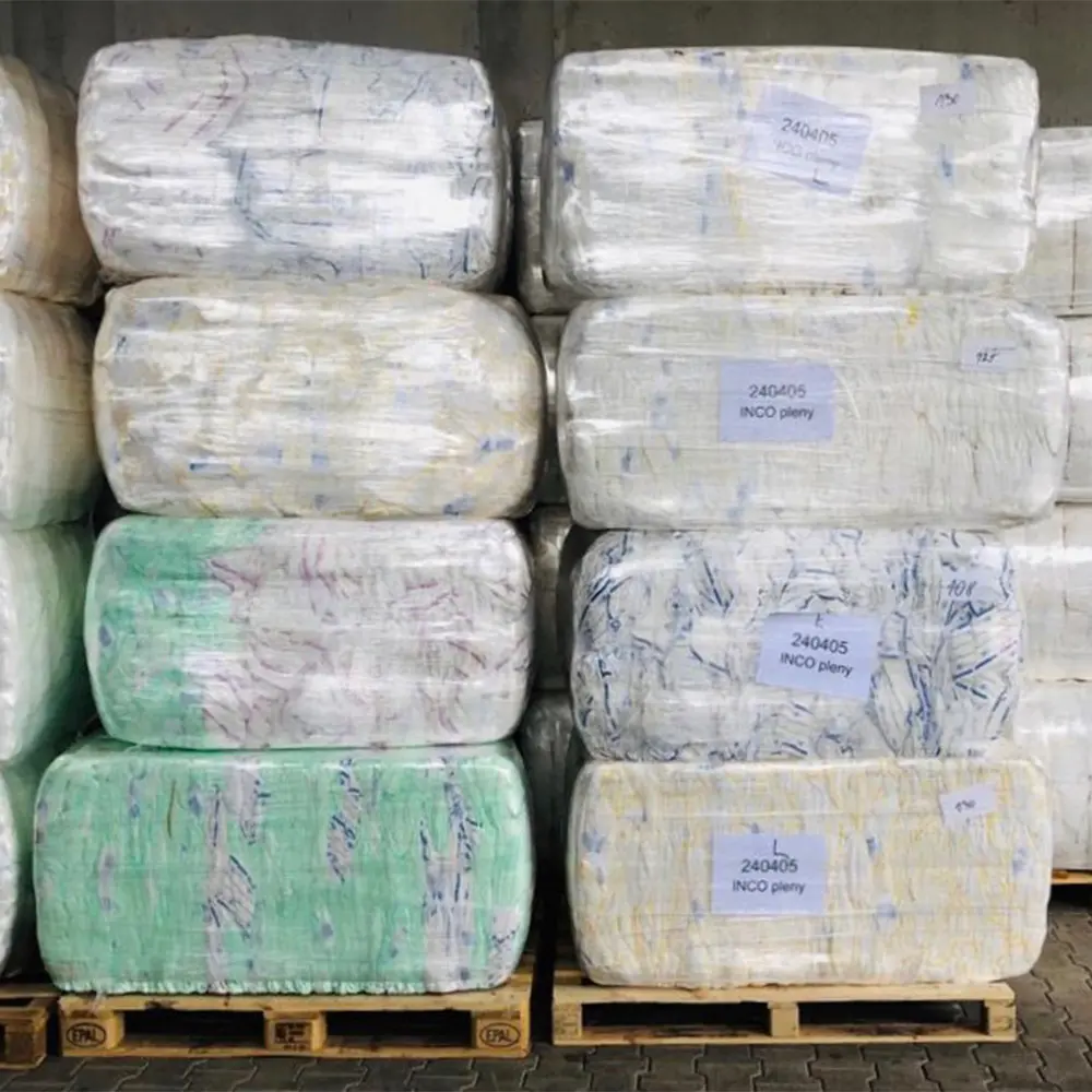 Stacked pallets wrapped in clear plastic containing large rectangular bales of materials with labels.