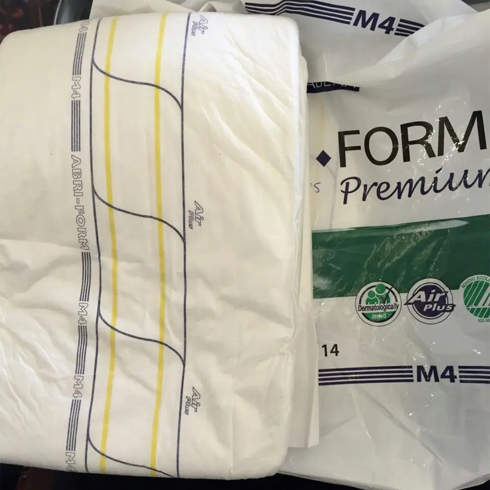 Folded white adult diaper with yellow and gray lines labeled M4 Abri-Form on top of a plastic package showing dermatologically tested and Air Plus logos.