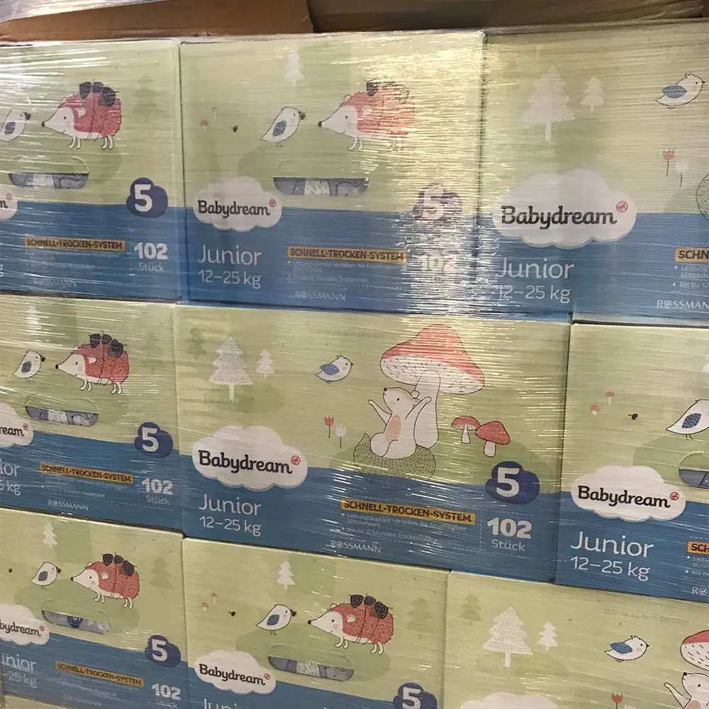 Stack of Babydream Junior size 5 diapers for 12-25 kg, packaged in boxes with animal and nature illustrations.