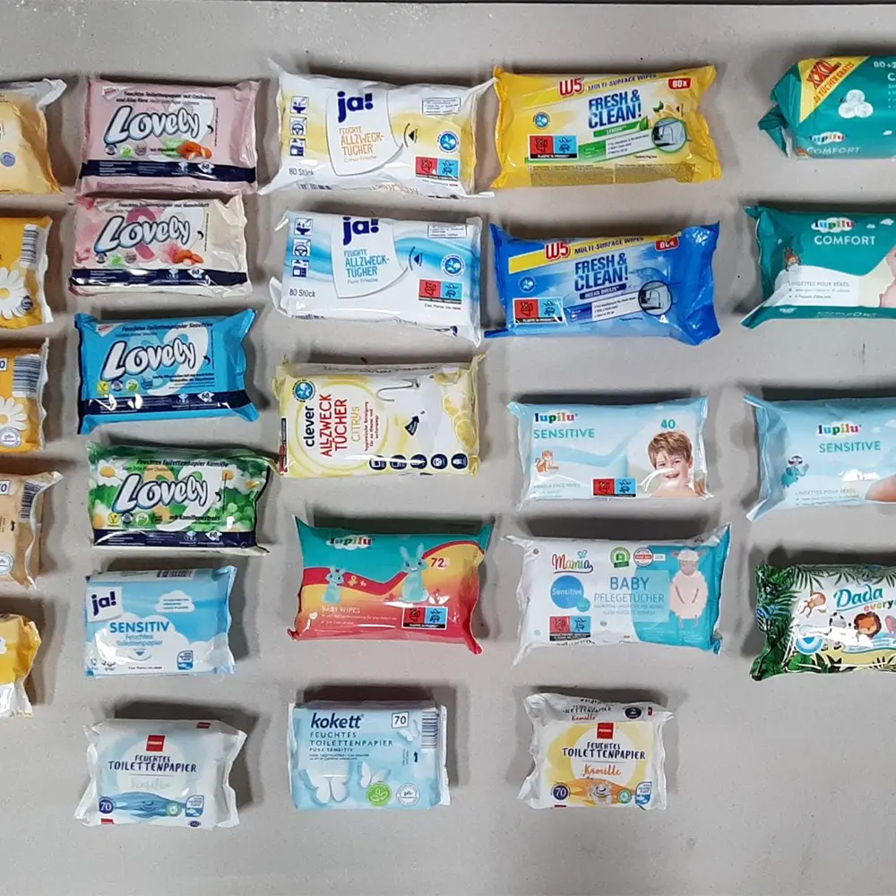 Assorted packaged wipes and toilet paper products arranged in a grid on a light surface.