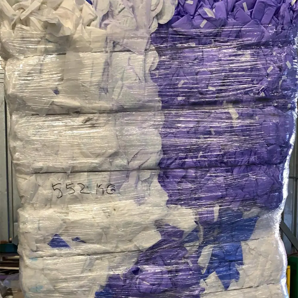 Stacked bales of compressed white and purple fabric wrapped in clear plastic with '552 kg' written on the plastic wrapping.