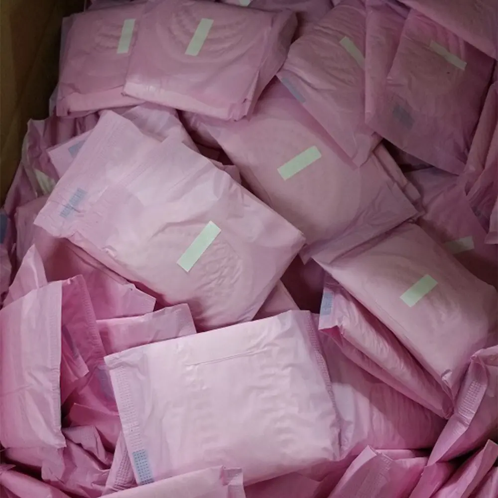 Multiple pink packaged sanitary pads stacked together in a box.