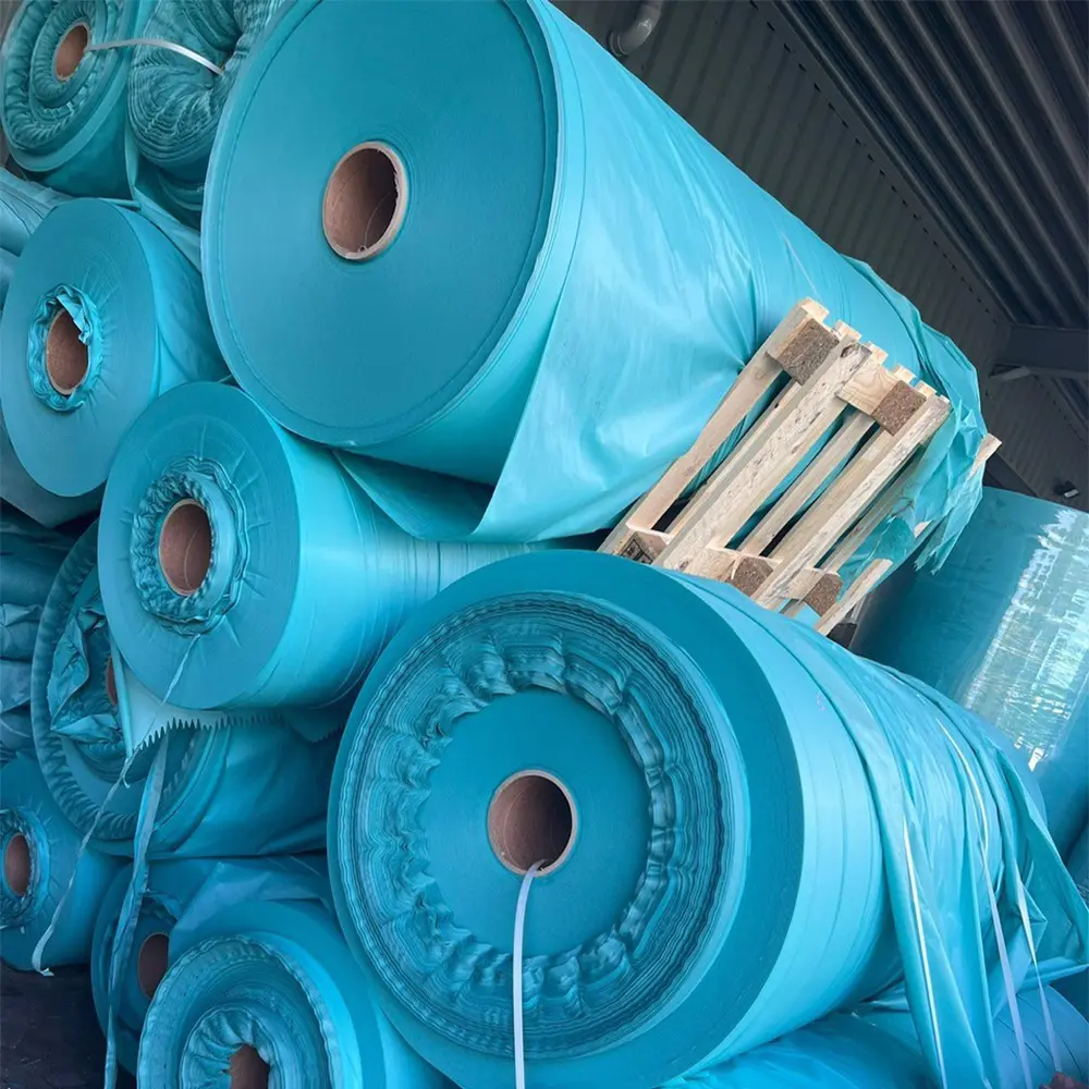 Large rolls of blue fabric or material stacked in a warehouse.